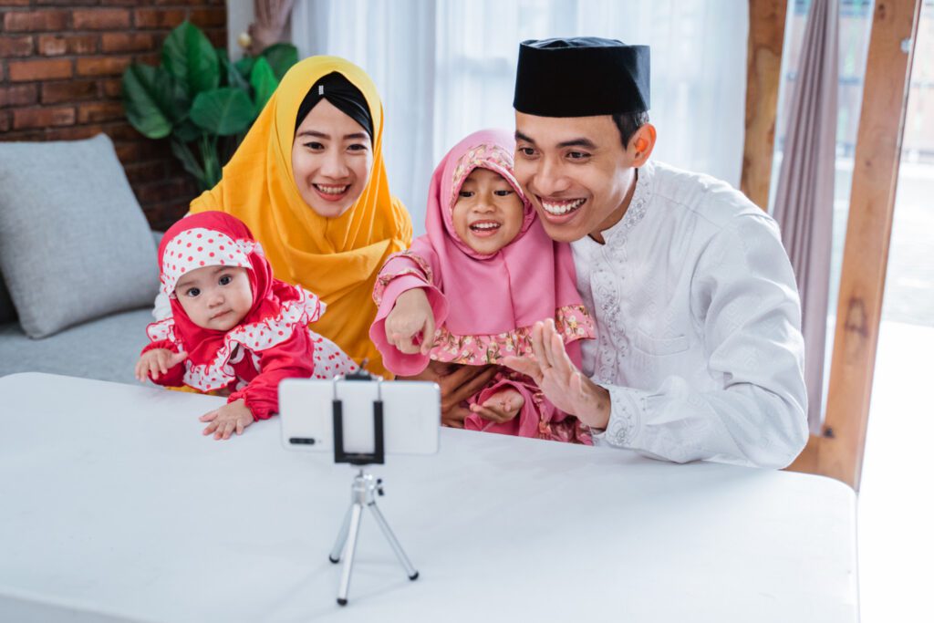 Istri yang baik menurut islam yang sedang menonton video dari smartphone bersama anak dan suaminya