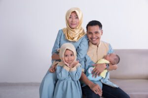Seorang istri yang baik menurut islam sedang berpose foto bersama anak dan suaminya