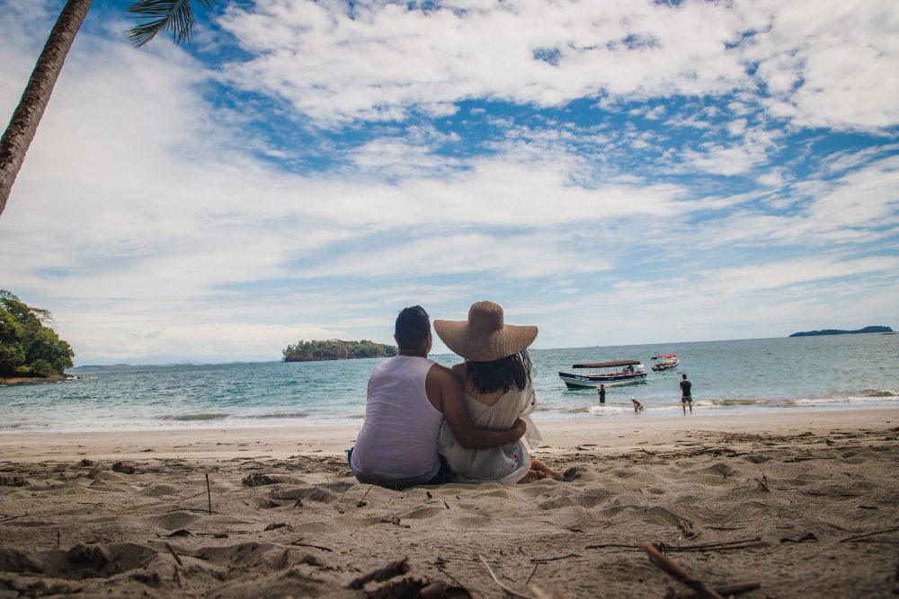 pasangan muda duduk ditepi pantai